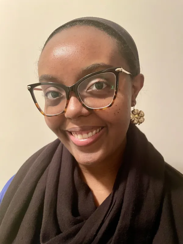 Photo of Joy Peltier, a Black woman in glasses, smiling at the camera.