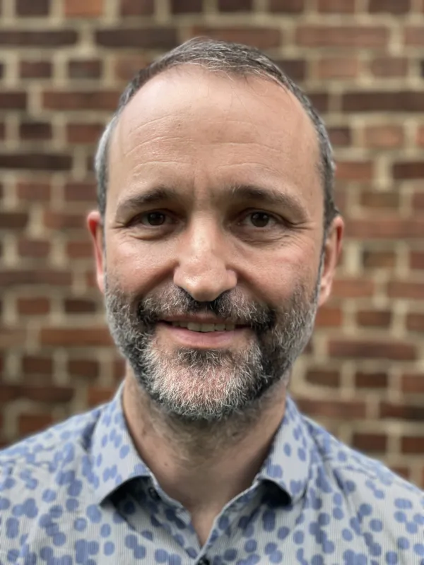 This picture shows a man in a blue shirt; he also has a beard.